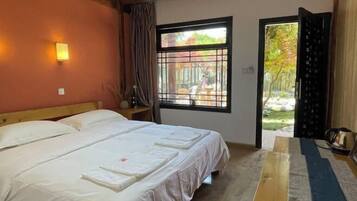 A bedroom with a bed, a window with a view of the outdoors, and a door leading to a balcony.