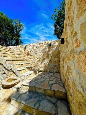 A stone staircase leading up a hill, surrounded by trees and a clear blue sky.
