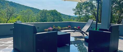 Eine Dachterrasse mit Pool, Liegestühlen und Topfpflanzen.
