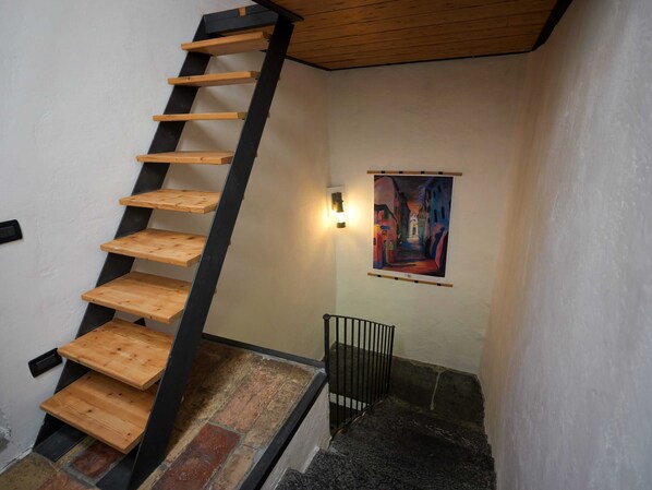 Una scala in legno con ringhiere nere e un quadro appeso al muro.