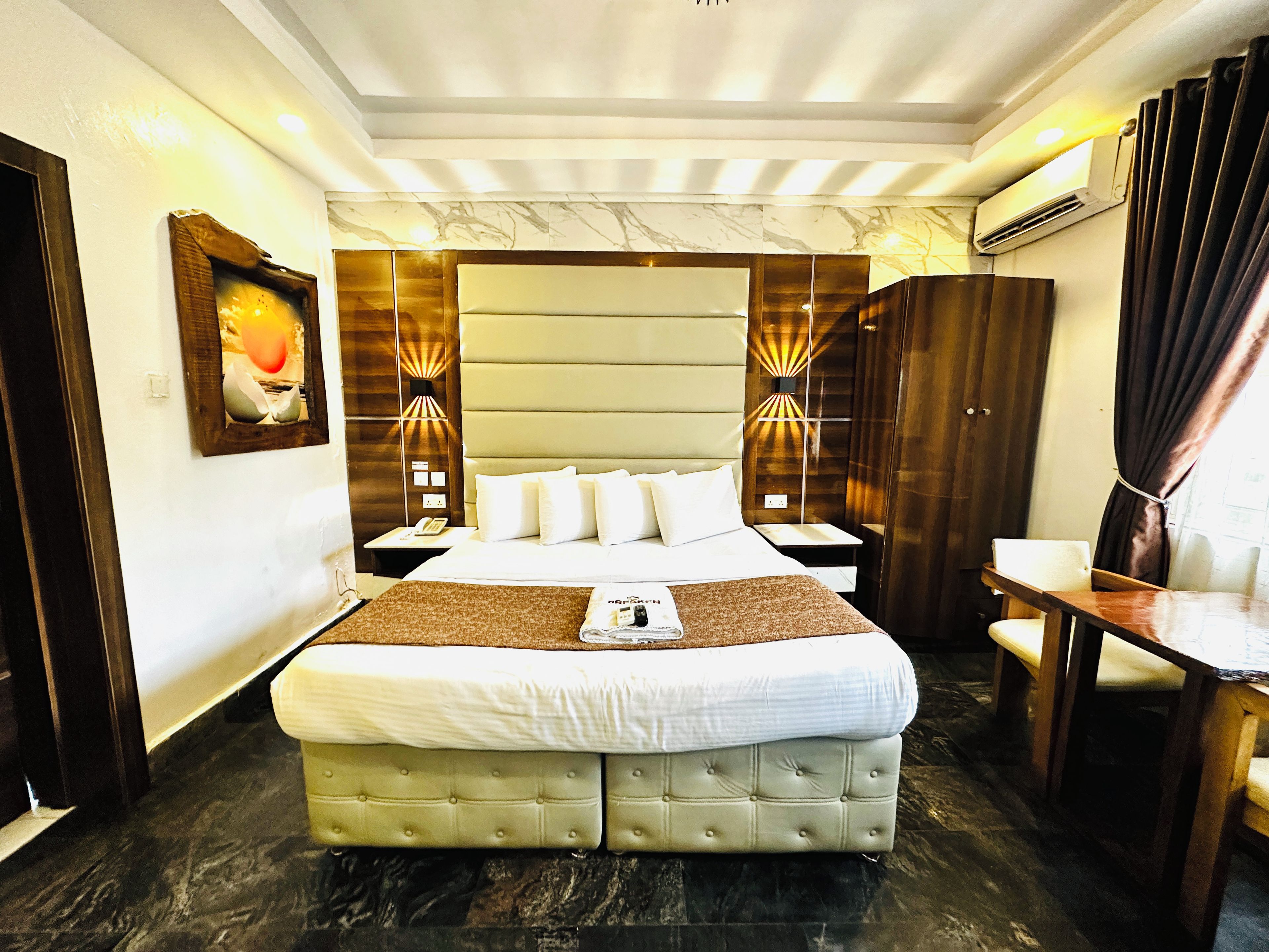 A hotel room with a large bed, bedside tables, a desk, and a chair.