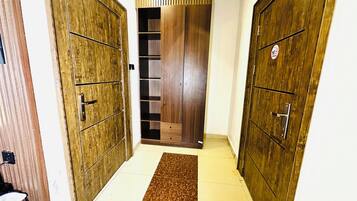 A hallway with wooden doors, a tiled floor, and a brown rug.