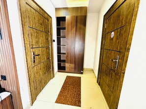 A hallway with wooden doors, a tiled floor, and a brown rug.