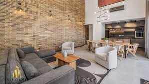 A modern living room with a brick wall, a dining area with a wooden table, and a kitchen with built-in appliances. - High ceilings & modern apt/BBQ - Morph 201 (Medellín)