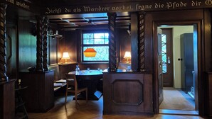 A warmly lit interior with wooden beams, a chandelier, and a patterned rug on a wooden floor. - Landhaus Hillehof Gruppenhaus mit Großem Garten und Panorama-aussicht (Bad Schandau)