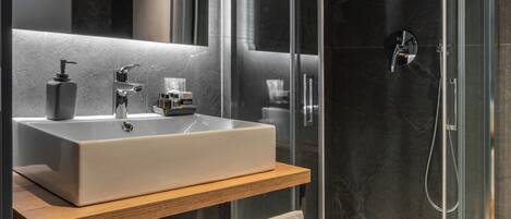 A modern bathroom with a glass-enclosed shower, a large sink, and a mirror above it.