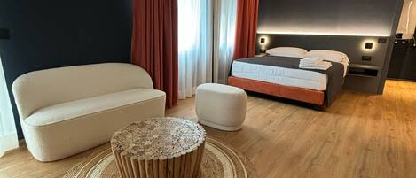 Une chambre moderne avec un grand lit, un canapé, une table basse ronde et une grande fenêtre avec des rideaux.