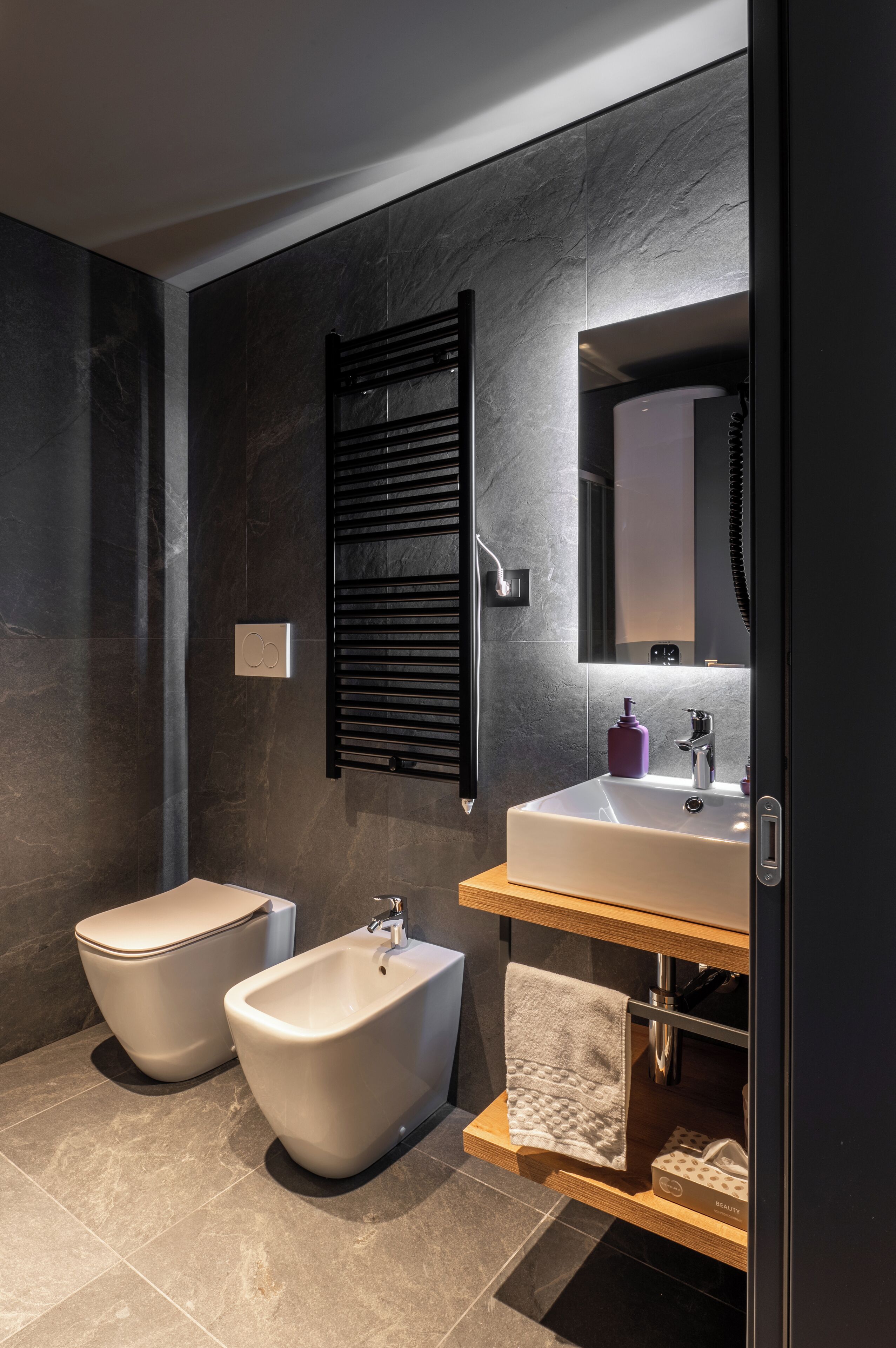 A modern bathroom with a bidet, a sink, and a mirror.