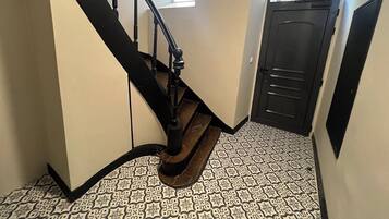 A staircase with a black handrail and wooden steps, leading to a door with a window above it.