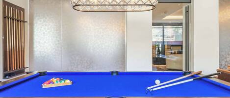 A pool table with a blue felt surface, a set of pool cues, and a rack of colorful balls.