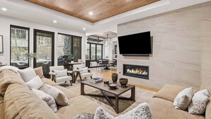 A modern living room with a fireplace, a large TV mounted on the wall, and a cozy seating area with a sofa and armchairs. - The Lion Residences W102 (Vail)