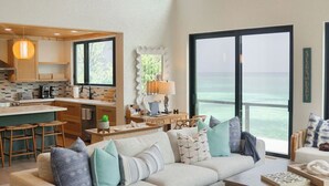A spacious living area with a large sectional sofa, a coffee table, and a view of the ocean through large windows. - Sweet Bahama Blue - Spanish Wells, Bahamas (Spanish Wells)