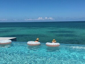 Una piscina con agua azul cristalina y vista al océano.