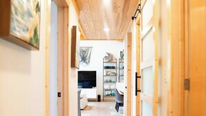 A hallway with wooden floors and walls, leading to a living area with a TV, shelves, and a rug. - Sweet Bahama Blue - Spanish Wells, Bahamas (Spanish Wells)