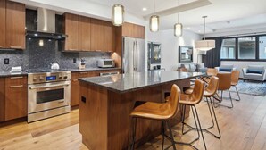 A modern kitchen with wooden cabinets, stainless steel appliances, and a large island with bar stools.