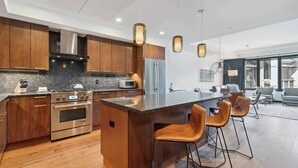 A modern kitchen with wooden cabinets, stainless steel appliances, and a central island with bar stools.