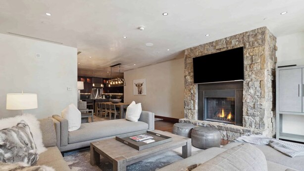 A modern living room with a stone fireplace, grey sofas, and a coffee table.