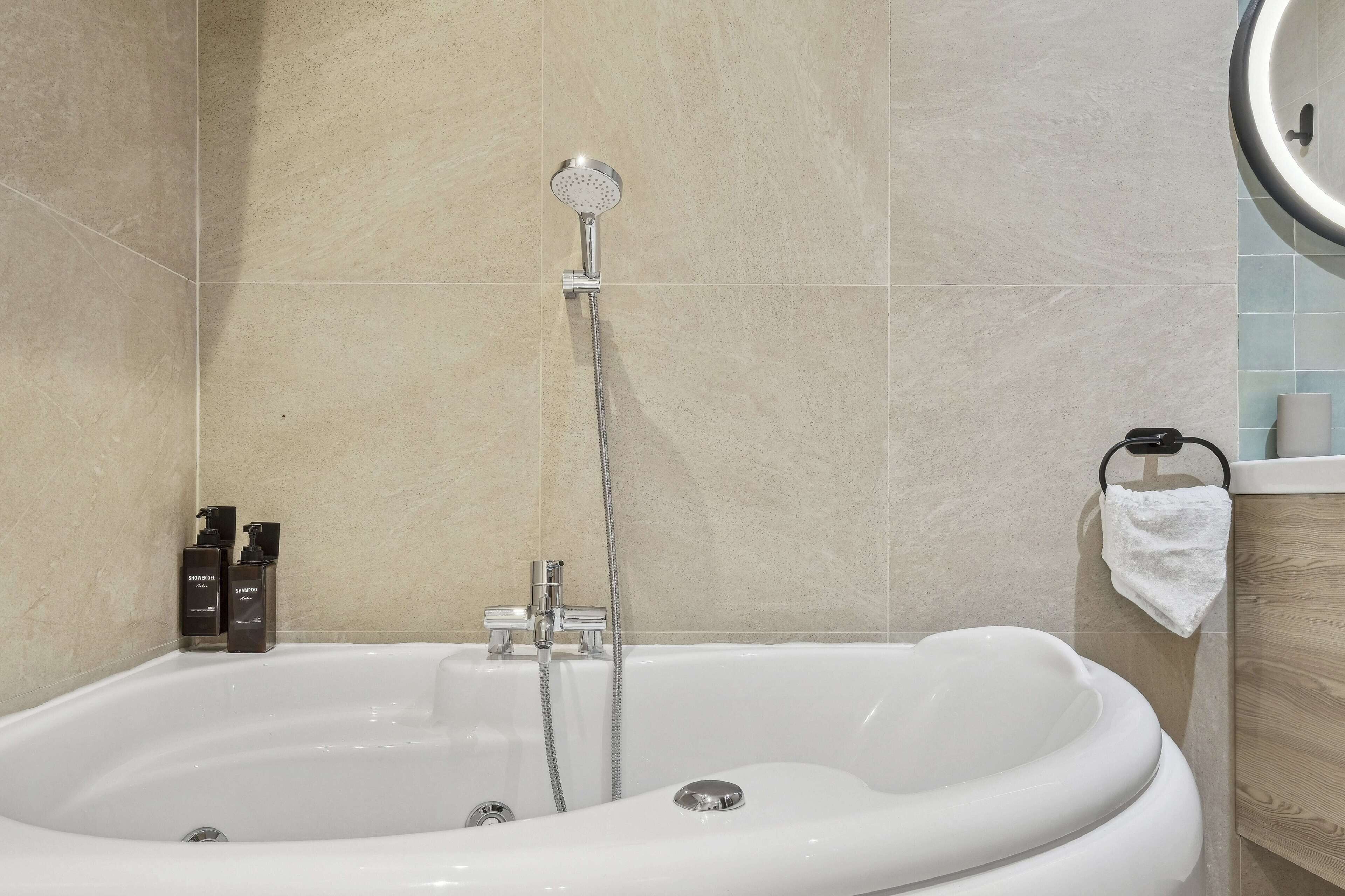 A modern bathroom with a freestanding bathtub, a handheld showerhead, and a towel rack.