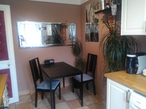 A small kitchen with a dining table and chairs, a coffee maker, and a refrigerator. - Paris Centre 14E Studio Avec Cuisine (Paris)