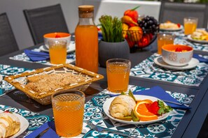 A table set with breakfast items including bread, fruit, and beverages. - Casa Joy (Lagoa)
