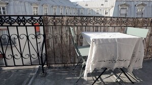 A rooftop terrace with a table set for dining, surrounded by a decorative fence and a wrought iron gate.