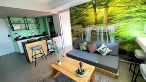 Un espacio de estar moderno con cocina, comedor y un gran mural de una cascada en un bosque.