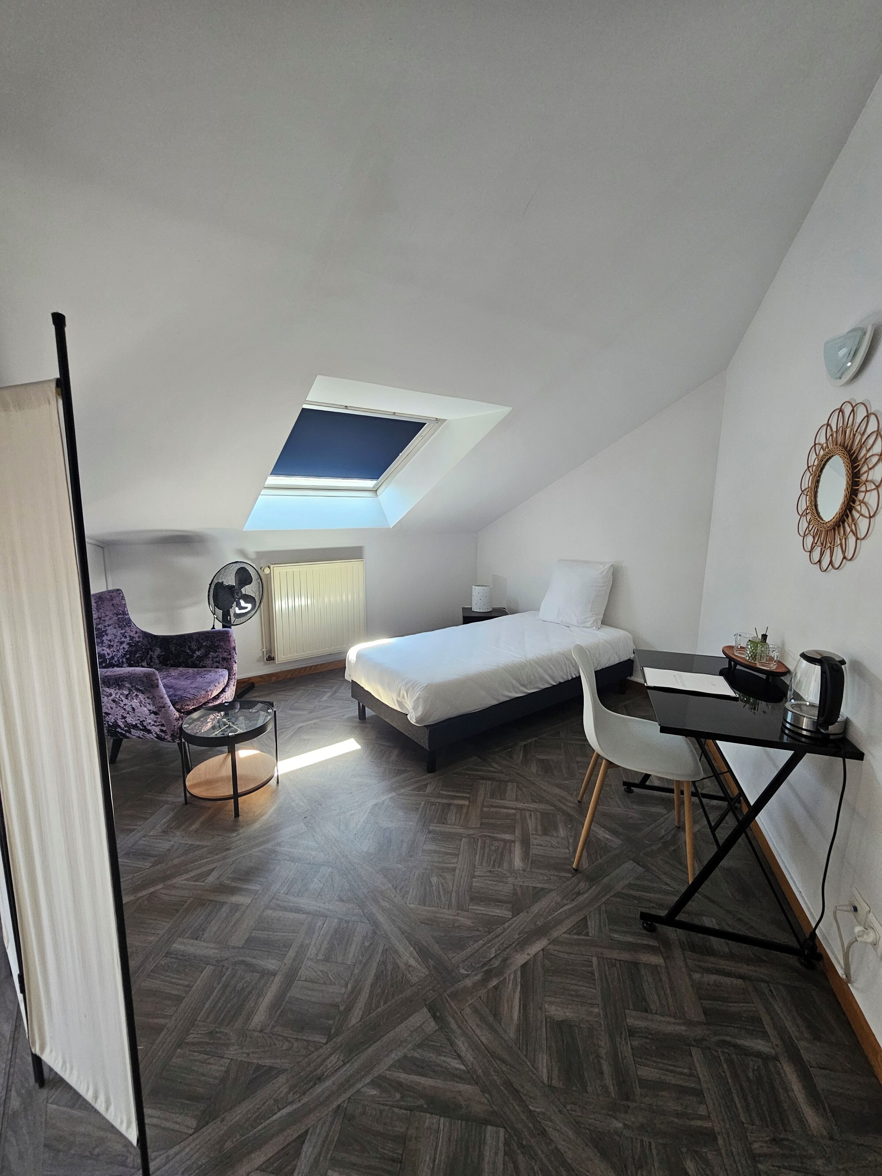 A compact room with a loft bed, a small desk, a chair, and a ceiling fan.