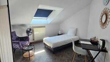 A compact room with a loft bed, a small desk, a chair, and a ceiling fan.