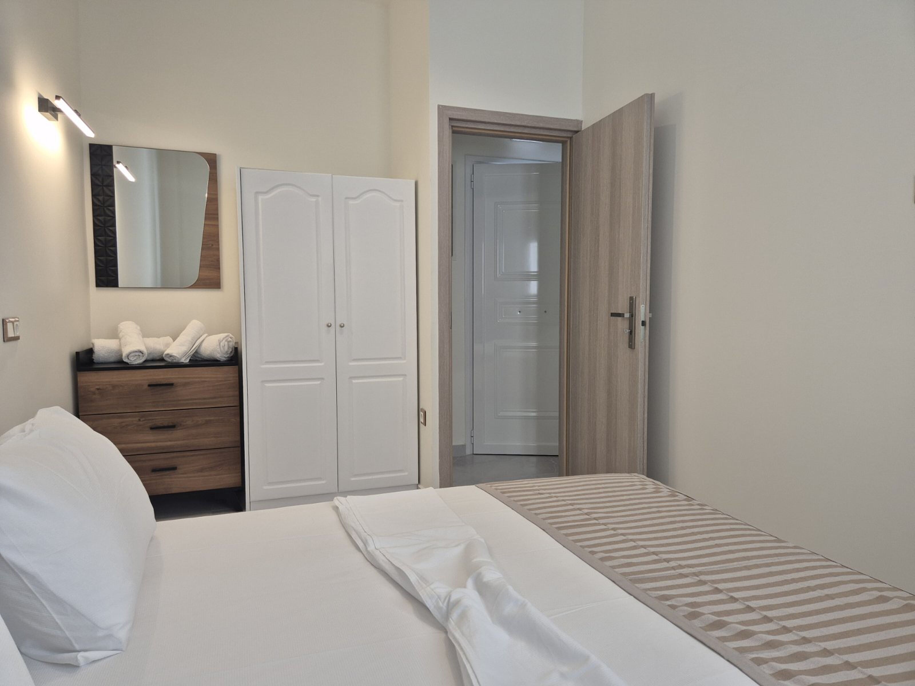 A bedroom with a bed, a wardrobe, a mirror, and a door.
