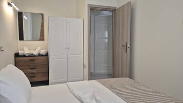 A bedroom with a bed, a wardrobe, a mirror, and a door.