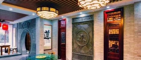 A traditional interior with a wooden ceiling, a round table with a glass top, and a decorative door.