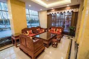 A traditional wooden sofa set with cushions, a glass-top coffee table, and a small round table with a chair.