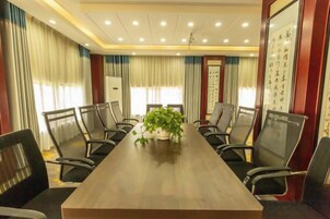 Un salón de conferencias con una larga mesa, sillas y una planta en maceta.