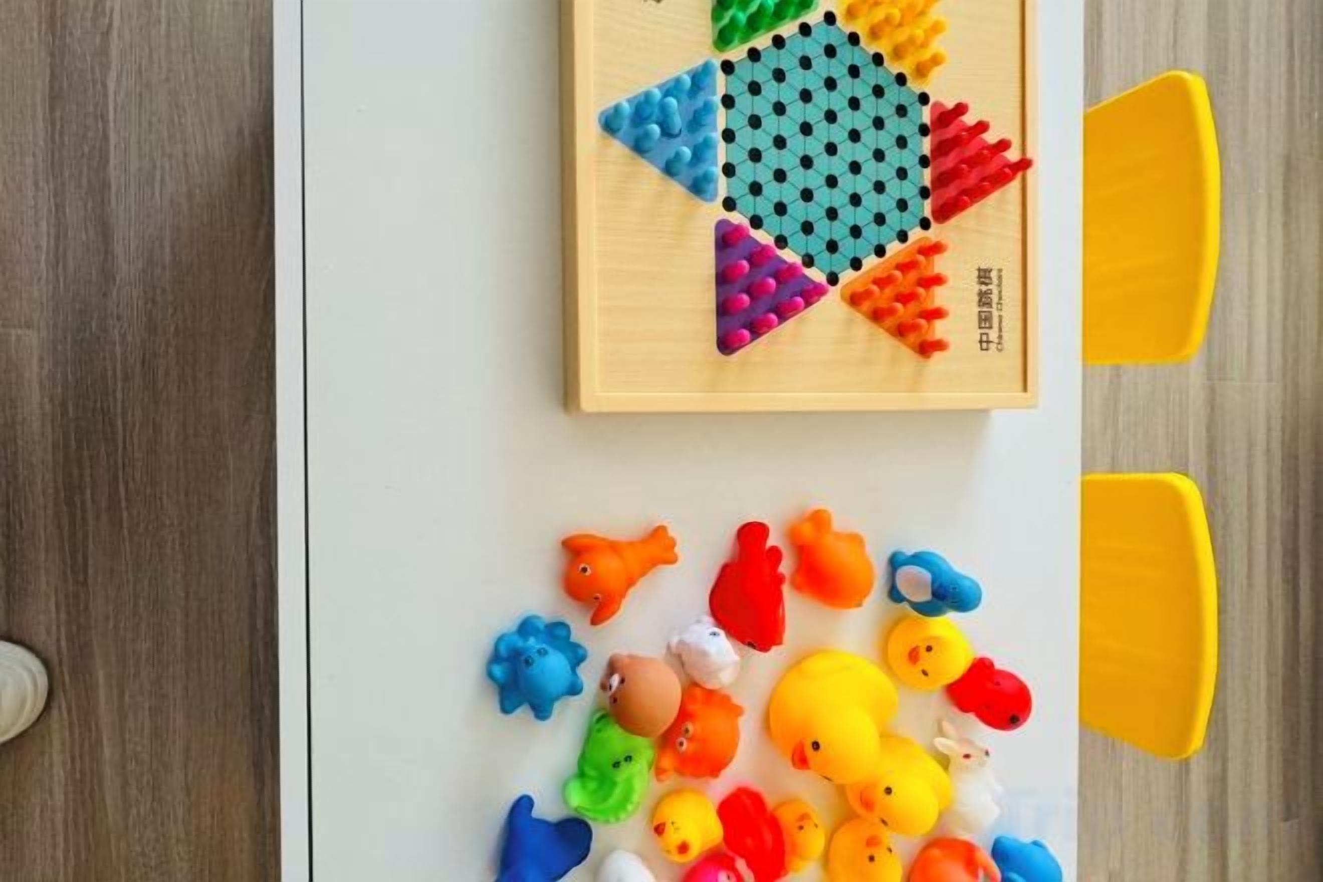 A wooden play mat with colorful toys scattered on a white surface.