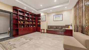 A spacious living area with a red bookshelf, a beige sofa, and a patterned rug.