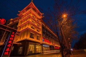 A traditional multi-story building with a distinct architectural style, featuring a prominent entrance and signage. - Dunhuang Tianqin Yunshui Hotel (Dunhuang)