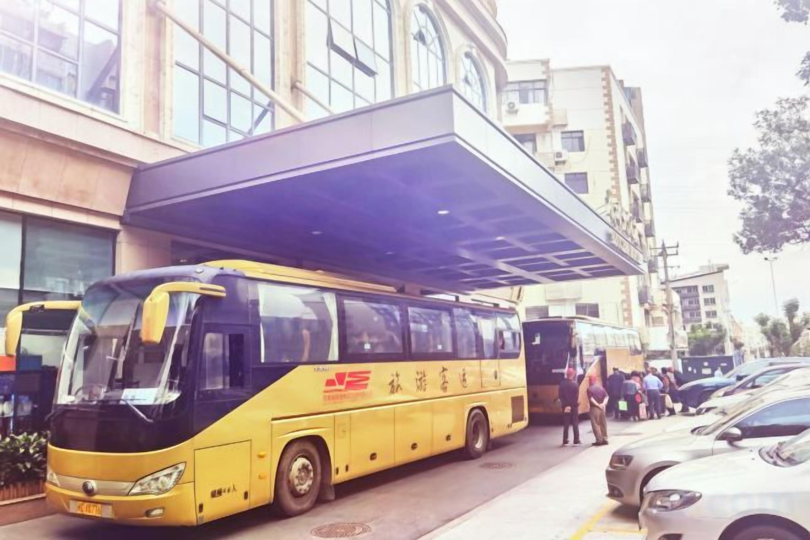 A yellow bus parked in front of a building with a covered entrance.