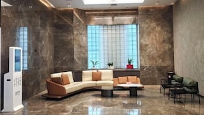 A modern lobby with a curved sofa, a coffee table, and a seating area with chairs. - Chenggong Hotel (Xiamen Gaoqi Airport SM Plaza) (Xiamen)