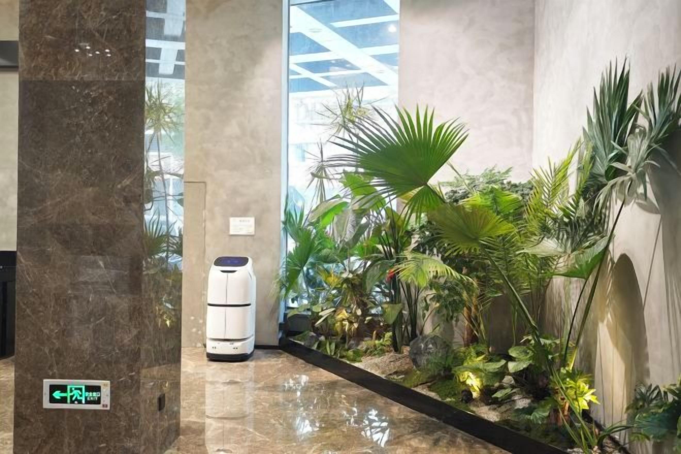 A hallway with a marble floor, a white air purifier, and a variety of indoor plants.