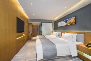 A modern hotel room with a large bed, a flat-screen TV mounted on the wall, and a painting above the bed. - Chenggong Hotel (Xiamen Gaoqi Airport SM Plaza) (Xiamen)