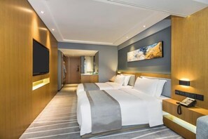 A modern hotel room with a large bed, a bedside table with a lamp, a flat-screen TV mounted on the wall, and a painting above the bed. - Chenggong Hotel (Xiamen Gaoqi Airport SM Plaza) (Xiamen)