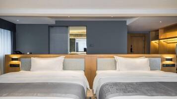 A hotel room with two beds, a wooden headboard, bedside lamps, and a mirror.