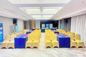A conference room with rows of yellow chairs, a stage with a podium, and a large screen. - Chenggong Hotel (Xiamen Gaoqi Airport SM Plaza) (Xiamen)