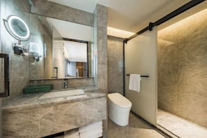 A modern bathroom with a marble sink, a large mirror with a light, a toilet, and a glass shower enclosure. - Chenggong Hotel (Xiamen Gaoqi Airport SM Plaza) (Xiamen)