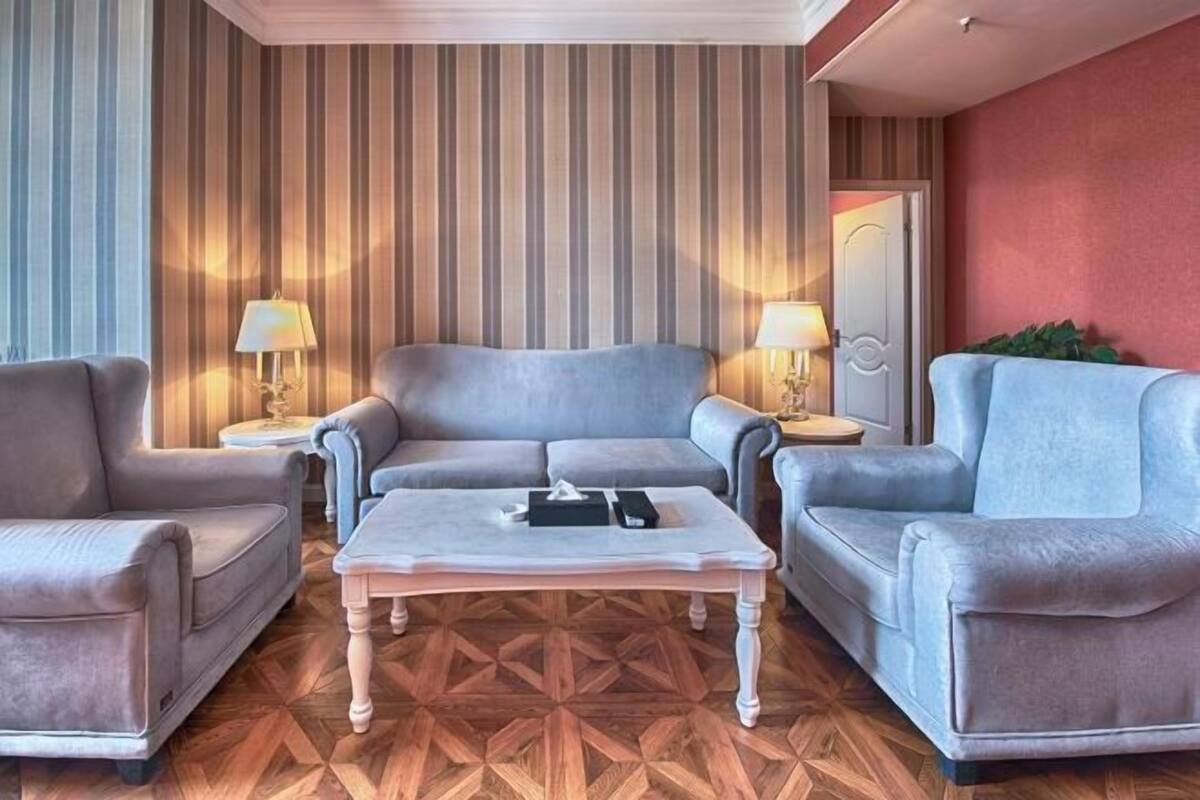 A living room with a sofa, two armchairs, a coffee table, and striped wallpaper.