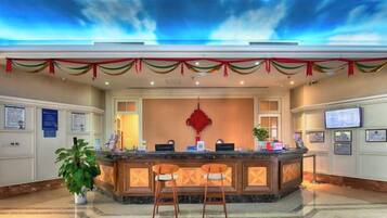 A hotel reception area with a counter, seating, and a decorative ceiling.