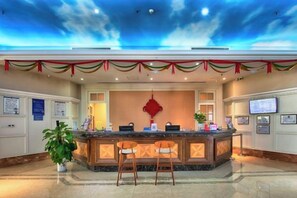 A hotel reception area with a counter, seating, and a decorative ceiling. - Xuzhou Amusement Land Resort Hotel (Xuzhou)