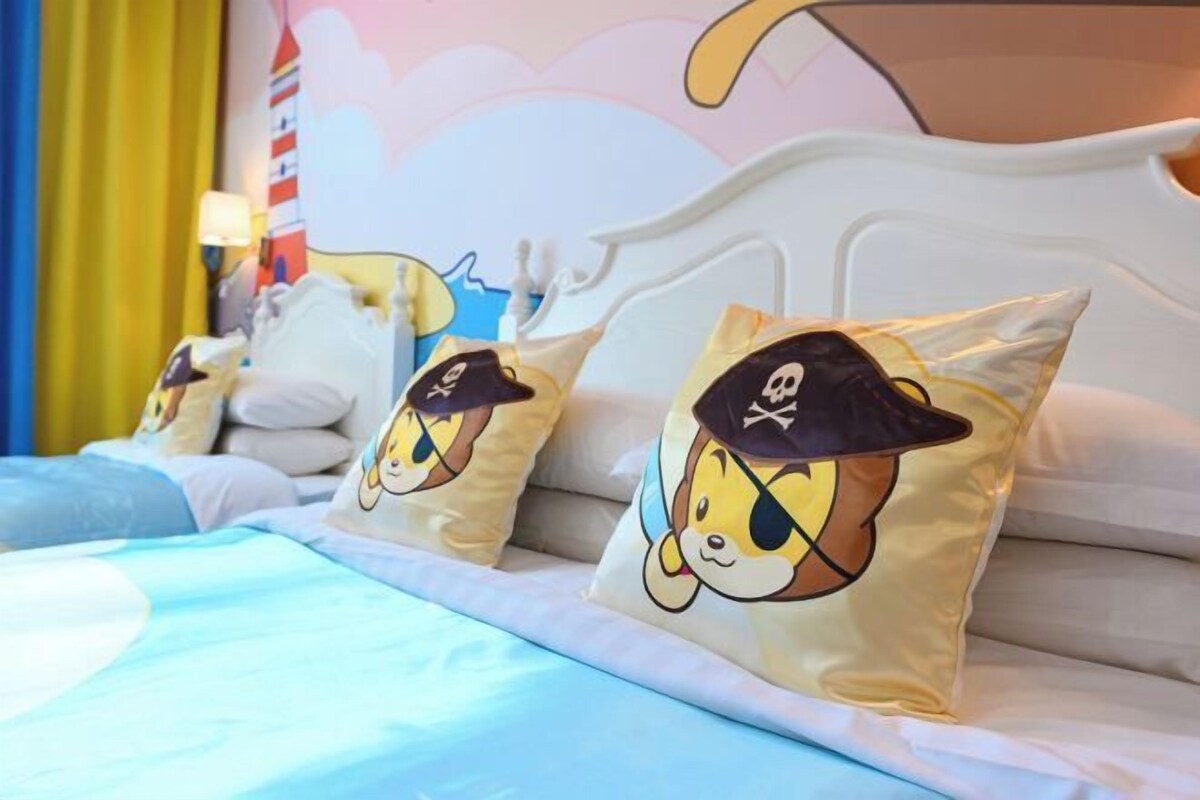 A bed with a white headboard, blue bedding, and three pillows with cartoon characters.