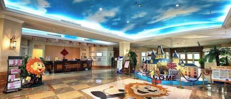 A hotel lobby with a check-in counter, a reception desk, and a decorative lion statue.