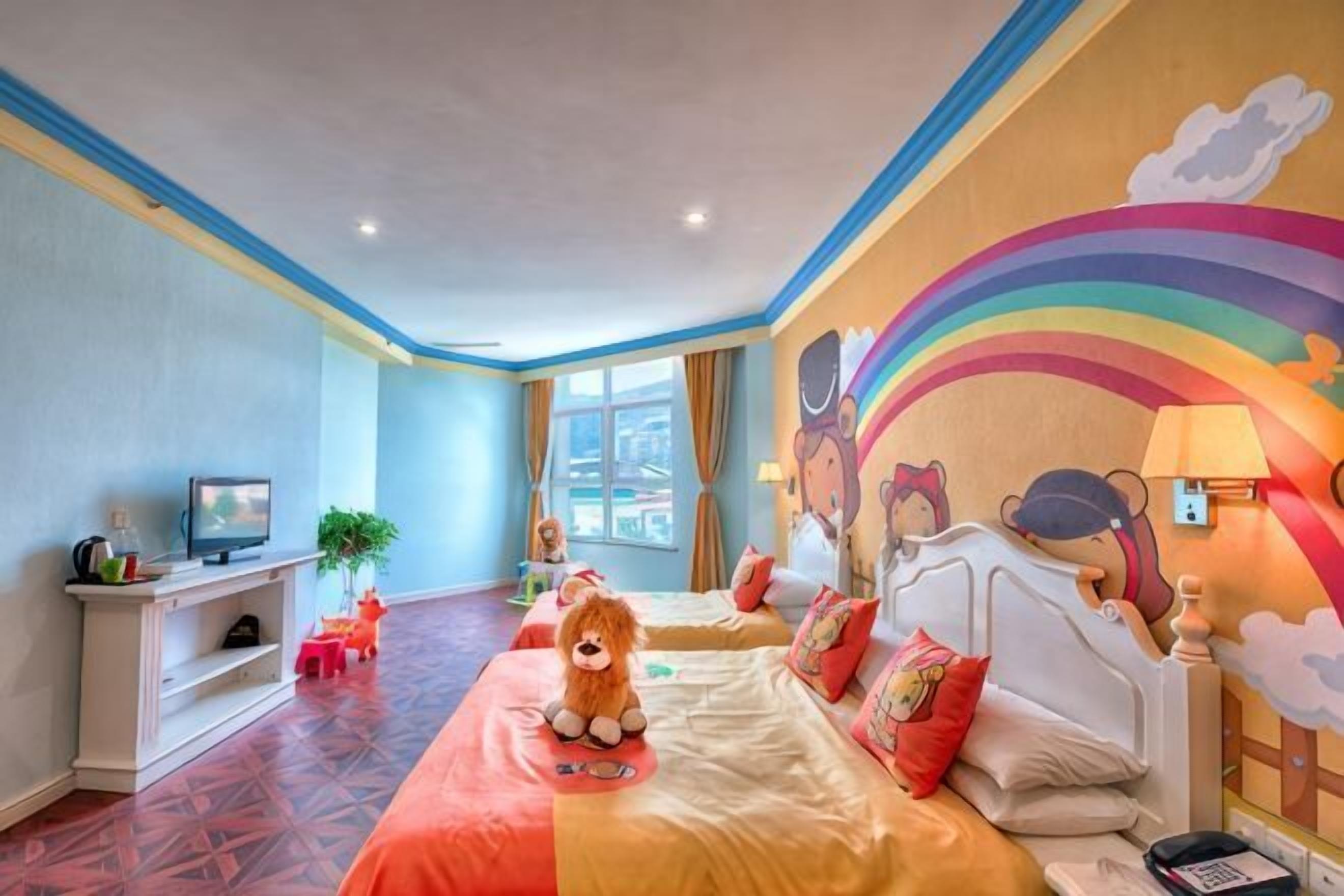 Ein Hotelzimmer mit zwei Betten, einem Fernseher, einem Schreibtisch und einem Fenster.